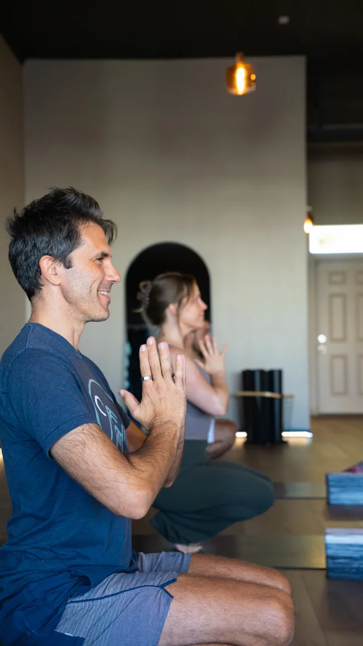 An instructor smiling with hands in prayer